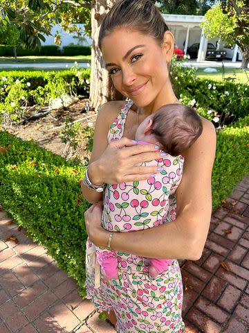 <p>Maria Menounos/Instagram</p> Maria Menounos cradles her daughter Athena against her chest.