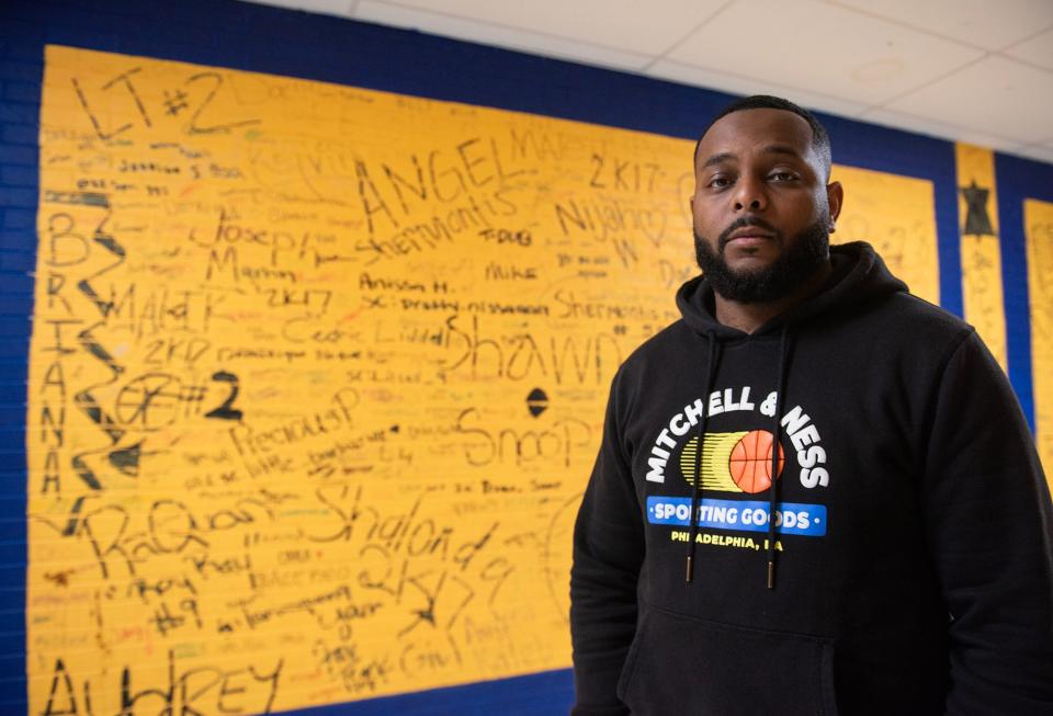 Coach and Teacher Jamario Winston poses for a photo in front of the senior memorial at Wingfield High School in Jackson on Tuesday, May 14, 2024. "It wasn't just a building for me," Giomario, who is also an alum, said about the school.