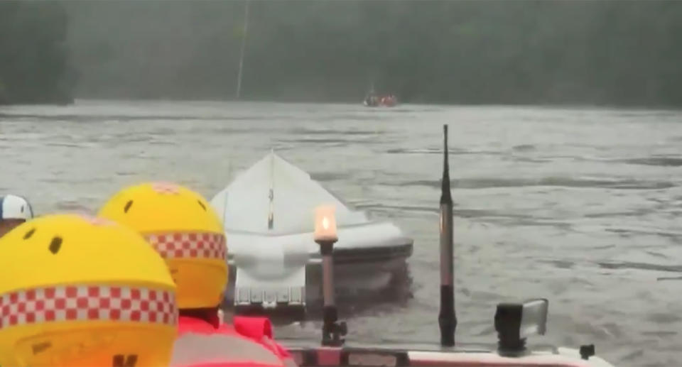 An emergency boat capsized in swollen flood waters while rescuing a family of four.