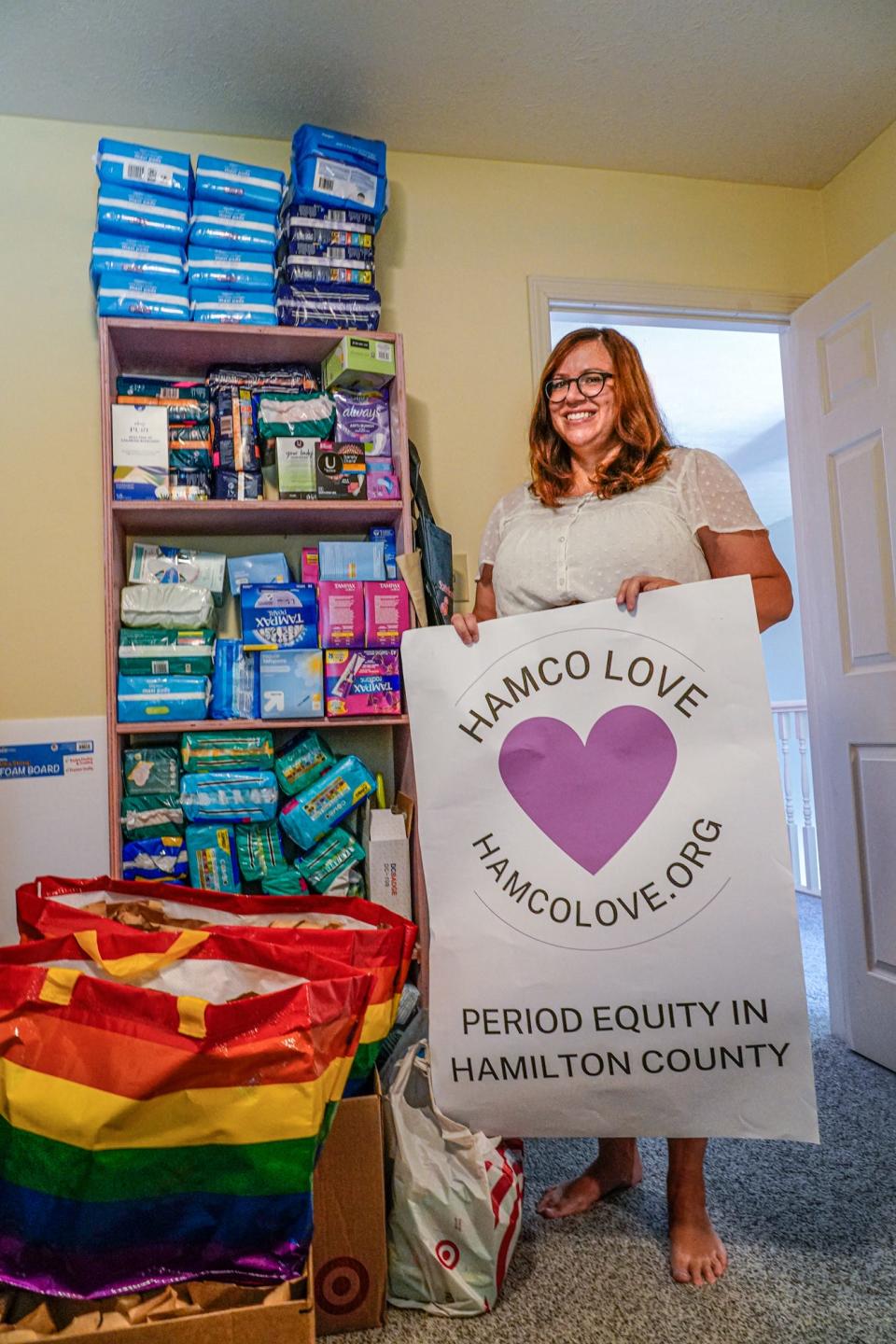 HamCo Love founder Jennifer Harmon holds a poster advertising the nonprofit's donated menstrual hygiene products, at her home on Tuesday, June 29, 2022. HamCo Love is a nonprofit based in Hamilton County which provides products for menstrual hygiene management. 