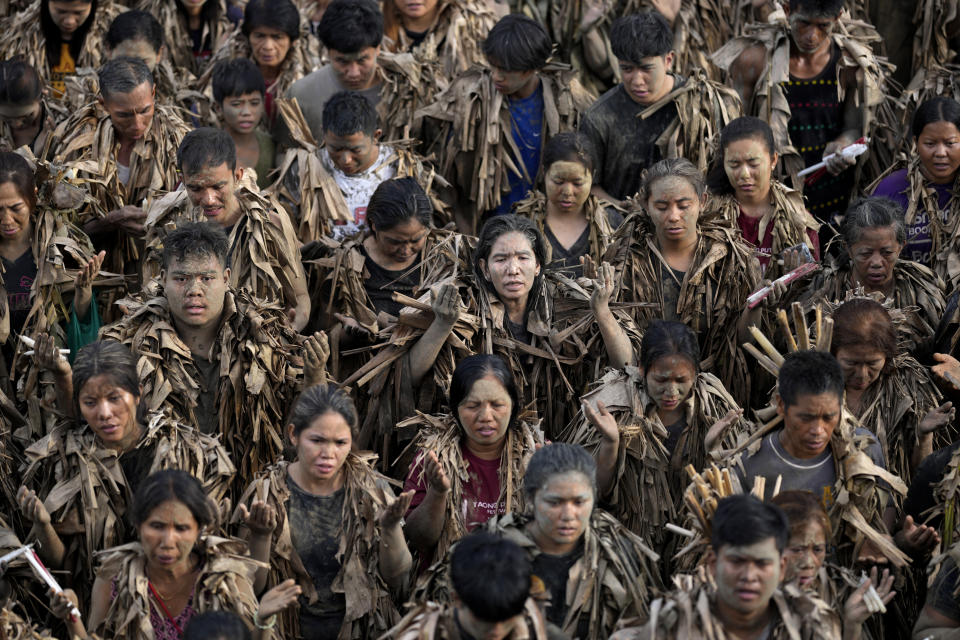 Devout Catholics, dressed in dried banana leaves, participate in mass at the church of Saint John the Baptist during the mud festival at Bibiclat, Nueva Ecija province, northern Philippines, Monday, June 24, 2024. (AP Photo/Aaron Favila)