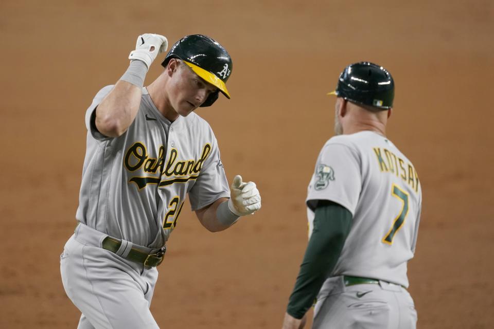 Oakland Athletics' Matt Chapman, left, and third base coach Mark Kotsay (7) celebrate Chapman's solo home run in the second inning of a baseball game against the Texas Rangers in Arlington, Texas, Saturday, Aug. 14, 2021. (AP Photo/Tony Gutierrez)