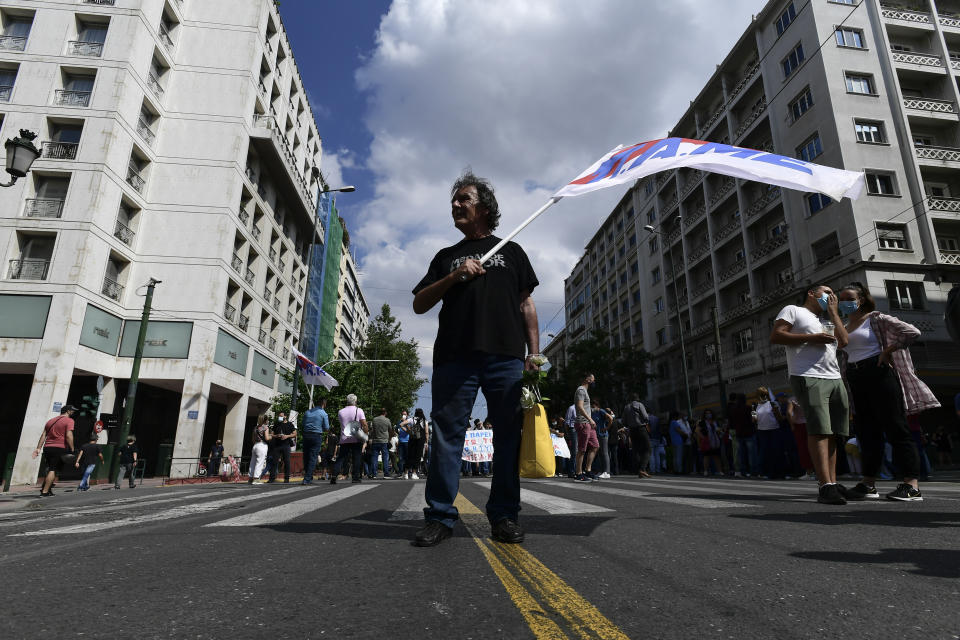 A protester raises a flag of the Greek communist party-affiliated PAME labor union during a rally in Athens, Thursday, June 10, 2021. Widespread strikes in Greece brought public transport and other services to a halt Thursday, as the country's largest labor unions protested against employment reforms they argue will make flexible workplace changes introduced during the pandemic more permanent. (AP Photo/Michael Varaklas)