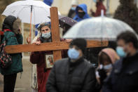 A man wearing a thorn crown and a mask for protection against COVID-19, holds a wooden cross while attending a religious service celebrating St. Andrew in the village of Ion Corvin, eastern Romania, Monday, Nov. 30, 2020. Braving wintry weather and the new coronavirus fears, several hundred Orthodox Christian believers gathered outside a cave in eastern Romania where St. Andrew is said to have lived and preached in the 1st century. (AP Photo/Vadim Ghirda)