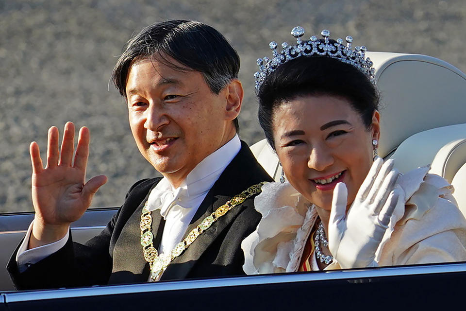 Japanese Emperor Naruhito, left, and Empress Masako, right, wave during the royal motorcade in Tokyo