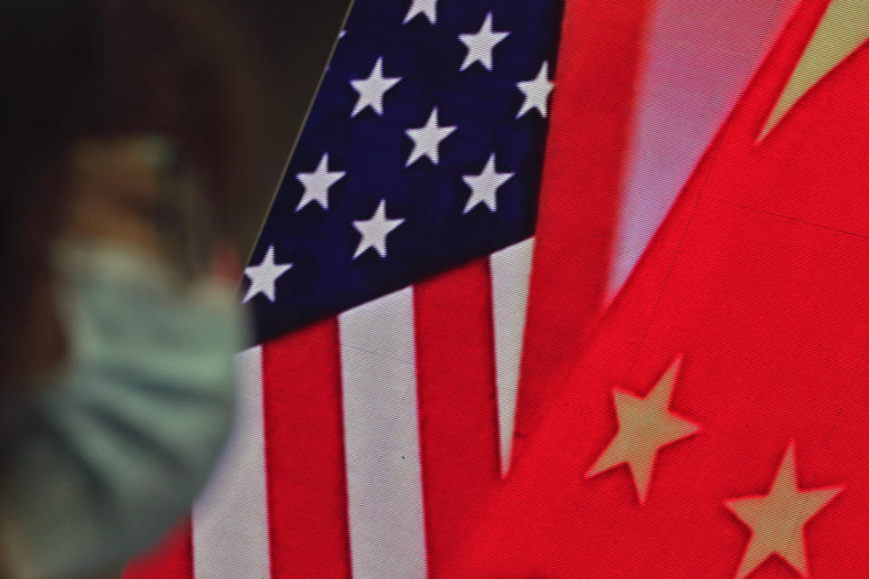 A woman wearing a face mask to help curb the spread of the coronavirus sits near a screen showing China and U.S. flags as she listens to a speech by Chinese Foreign Minister Wang Yi at the Lanting Forum on bringing China-U.S. relations back to the right track, at the Ministry of Foreign Affairs office in Beijing on Monday, Feb. 22, 2021. Foreign Minister Wang Yi called on the U.S. Monday to lift restrictions on trade and people-to-people contacts while ceasing what Beijing considers unwarranted interference in the areas of Taiwan, Hong Kong, Xinjiang and Tibet. (AP Photo/Andy Wong)