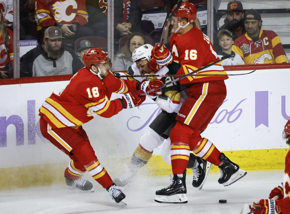 Vegas Golden Knights forward William Carrier, center, is checked by Calgary Flames forward A.J. Greer, left, and defenseman Nikita Zadorov during first-period NHL hockey game action in Calgary, Alberta, Monday, Nov. 27, 2023. (Jeff McIntosh/The Canadian Press via AP)