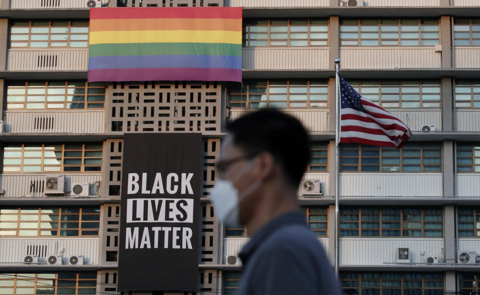 FILE - In this Sunday, June 14, 2020 file photo, a man walks near a giant Black Lives Matter and a rainbow banners at the U.S. Embassy in Seoul, South Korea. The banner was put up on Saturday with Ambassador Harry Harris tweeting that his embassy “stands in solidarity with fellow Americans grieving and peacefully protesting to demand positive change.” It, along with the rainbow flag, was taken down Monday. On Tuesday, a banner marking the upcoming 70th anniversary of the start of the Korean War adorned the Embassy.(AP Photo/Lee Jin-man, File)