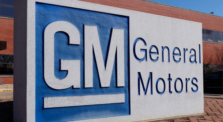 General Motors (GM) sign with blue and white logo and brick building in background