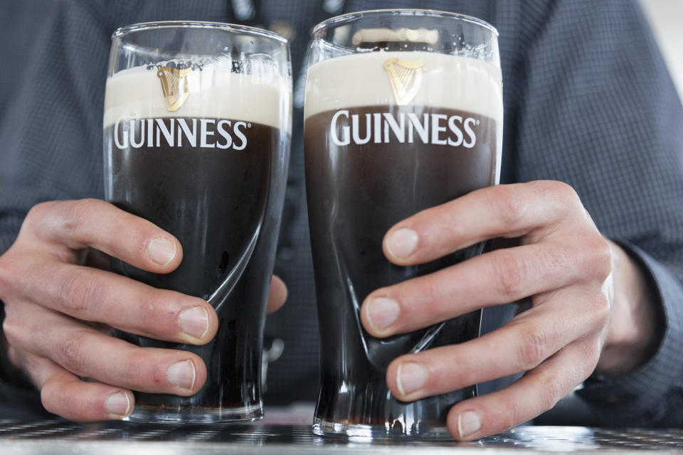 Close up of a hands holding two cold pints of Guinness.