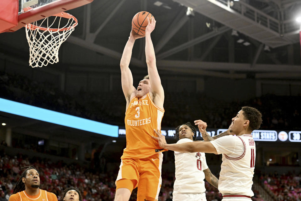 Tennessee guard Dalton Knecht (3) drives past Arkansas defenders Khalif Battle (0) and Jalen Graham (11) during the first half of an NCAA college basketball game Wednesday, Feb. 14, 2024, in Fayetteville, Ark. (AP Photo/Michael Woods)