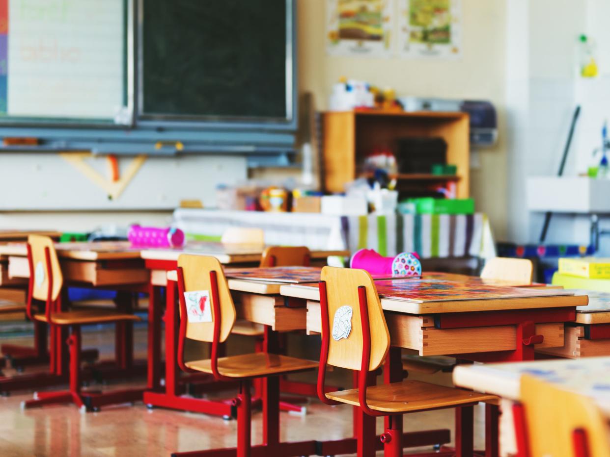 A colorful classroom with chairs, desks, supplies, and a blackboard.