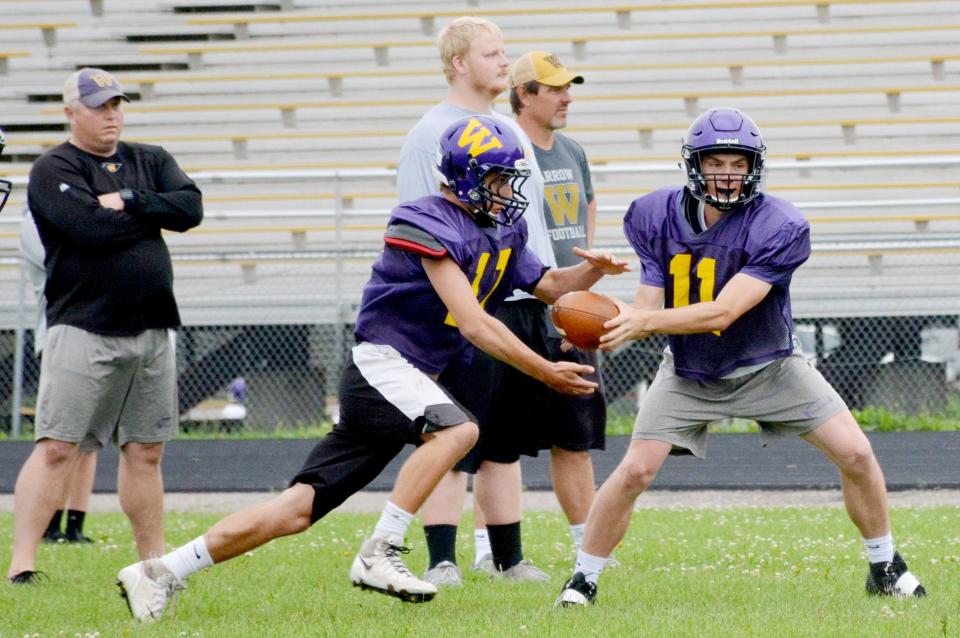 Quarterback Brandon Florey hands off to Mitchell Llloyd as coaches Matt Paulson, Tyler Robel and head coach John Hodorff look on during a practice for the 2018 Watertown High School football team.