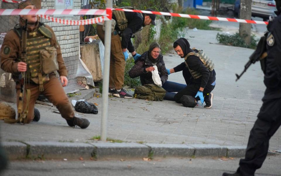 Medics help an injured woman after a drone fired on buildings in Kyiv - AP