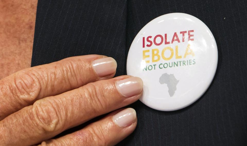 International Monetary Fund (IMF) Managing Director Christine Lagarde points to a button saying "Isolate Ebola, Not Countries" as she speaks during the IMFC news conference during the World Bank/IMF Annual Meeting in Washington October 11, 2014. REUTERS/Joshua Roberts (UNITED STATES - Tags: POLITICS BUSINESS)