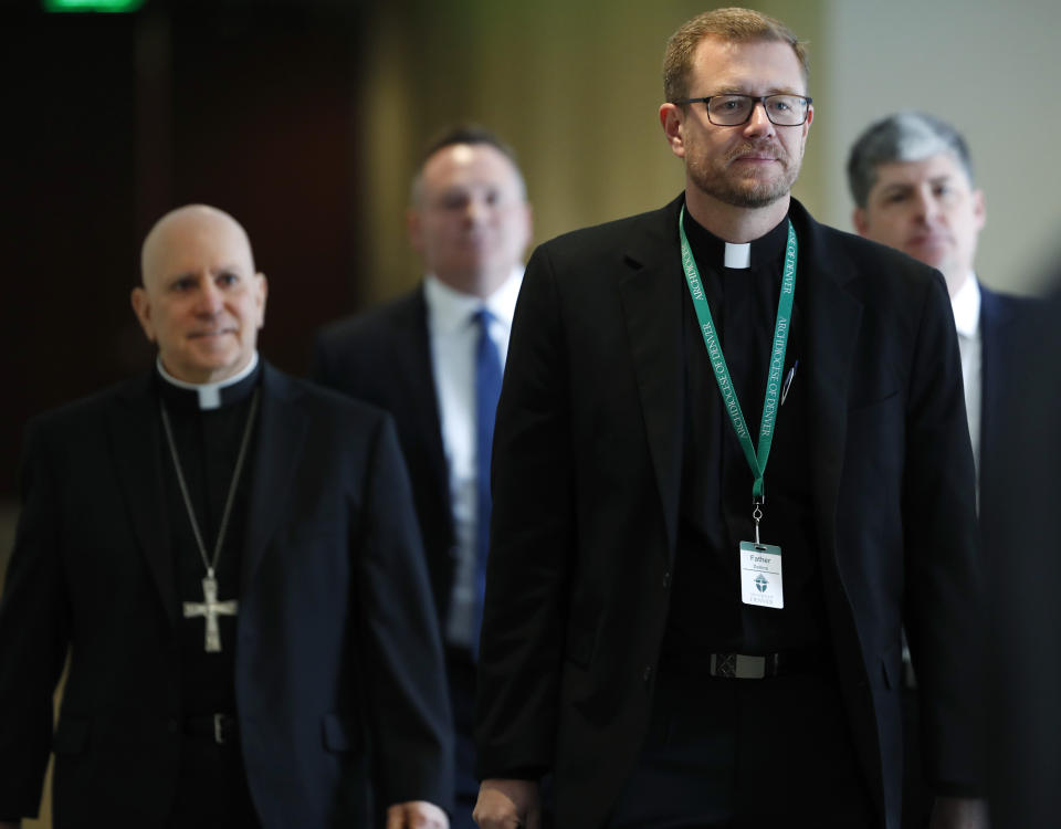 Samuel Aquila, archbishop of the Denver diocese of the Roman Catholic Church, follows Very Rev. Randy Dollins, vicar general, into a news conference to hear the plan to have a former federal prosecutor review the sexual abuse files of Colorado's Roman Catholic dioceses at a news conference Tuesday, Feb. 19, 2019, in Denver. The church will pay reparations to victims under a voluntary joint effort with the state attorney general. (AP Photo/David Zalubowski)