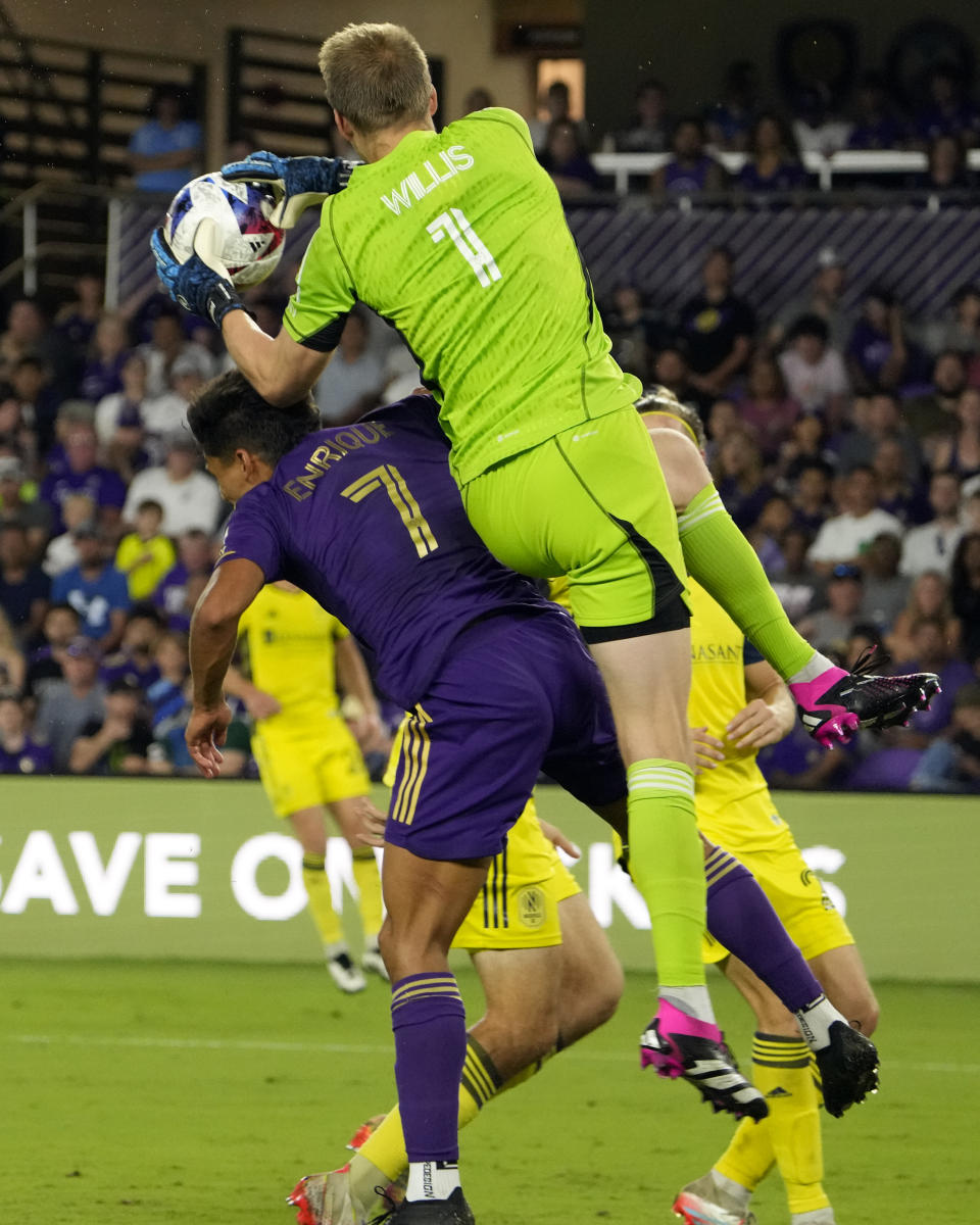 Nashville SC goalkeeper Joe Willis (1) leaps over Orlando City's Ramiro Enrique (7) to grab a pass during the second half of an MLS soccer match, Saturday, April 1, 2023, in Orlando, Fla. (AP Photo/John Raoux)