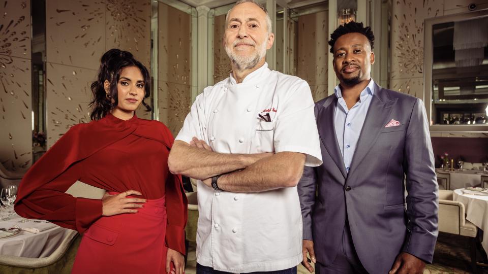 Ravneet Gill in a red top and skirt, Michel Roux Jr in chefs' white and Mike Reid in a dark suit in Five Star Kitchen