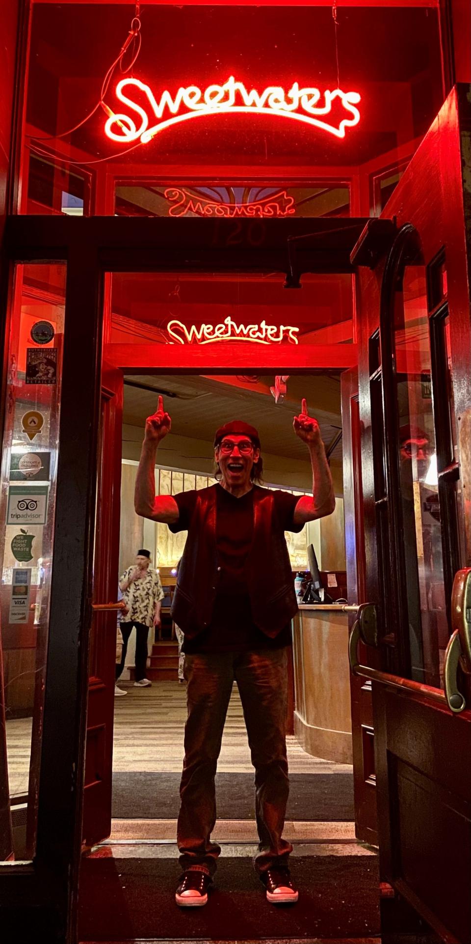 Former South Burlington resident Martin Guigui, writer and director of the film "Sweetwater," stands in June 2022 beneath a sign for the similarly-named, now-closed restaurant on Church Street in Burlington.