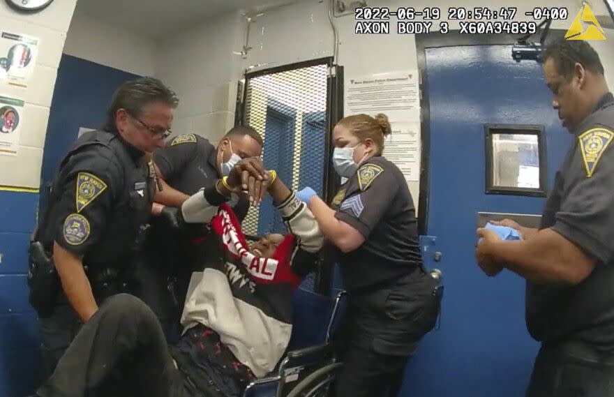 New Haven police officers lift Randy Cox into a wheelchair at the police station.