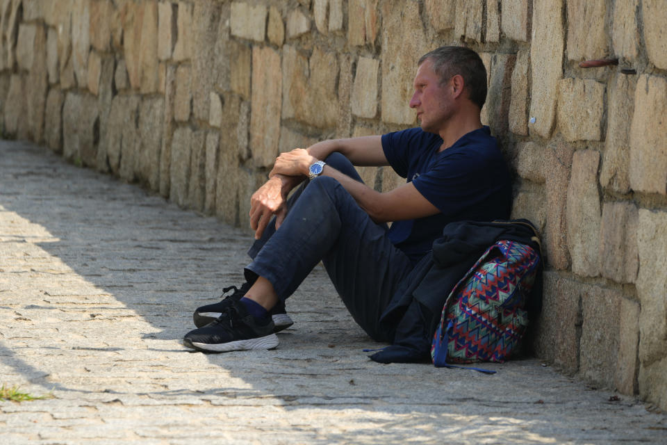 A man sits in the shade behind a wall during hot weather in Madrid, Spain, Wednesday, July 13, 2022. Weather forecasters say Spain is expected to have its second heat wave in less than a month and that it will will last at least until the weekend. Meteorologists said an overheated mass of air and warm African winds are driving temperatures in the Iberian Peninsula beyond their usual highs. (AP Photo/Paul White)