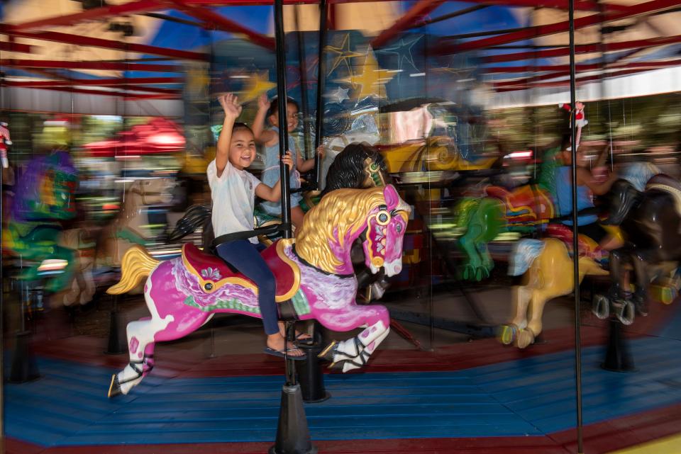 Camila Gomez, 6, near, of Stockton, and McKenna Wright, 3, of Manteca, ride on the carousel at the Christmas in July event at Pixie Woods on July 23.