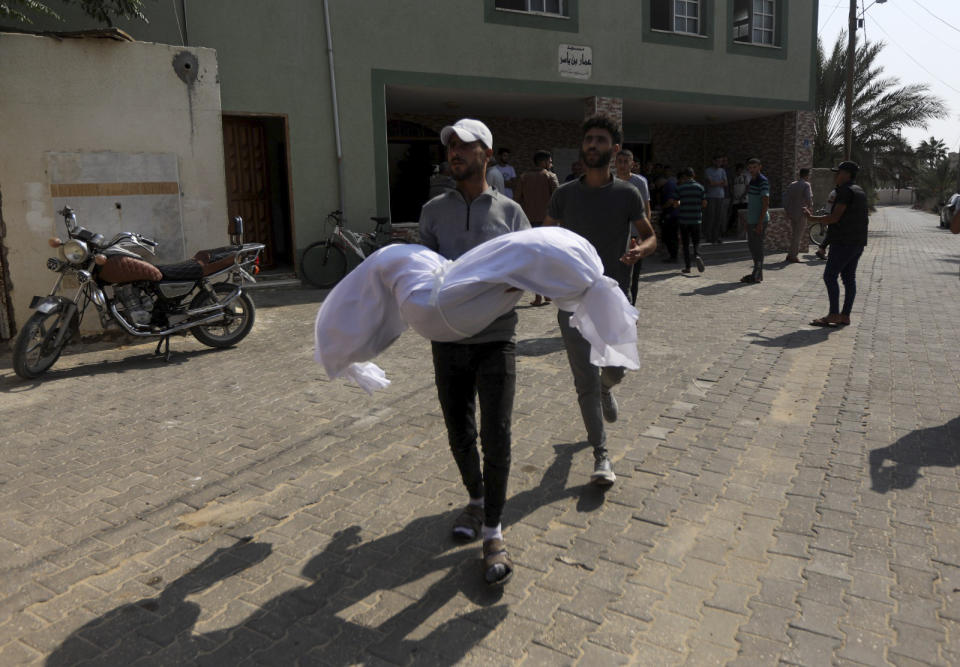 A relative carries a body of the Abu Dagga family who were killed in an Israeli airstrike y during their funeral in Khan Younis, southern Gaza Strip, Saturday, Oct. 7, 2023. (AP Photo/Yousef Masoud)