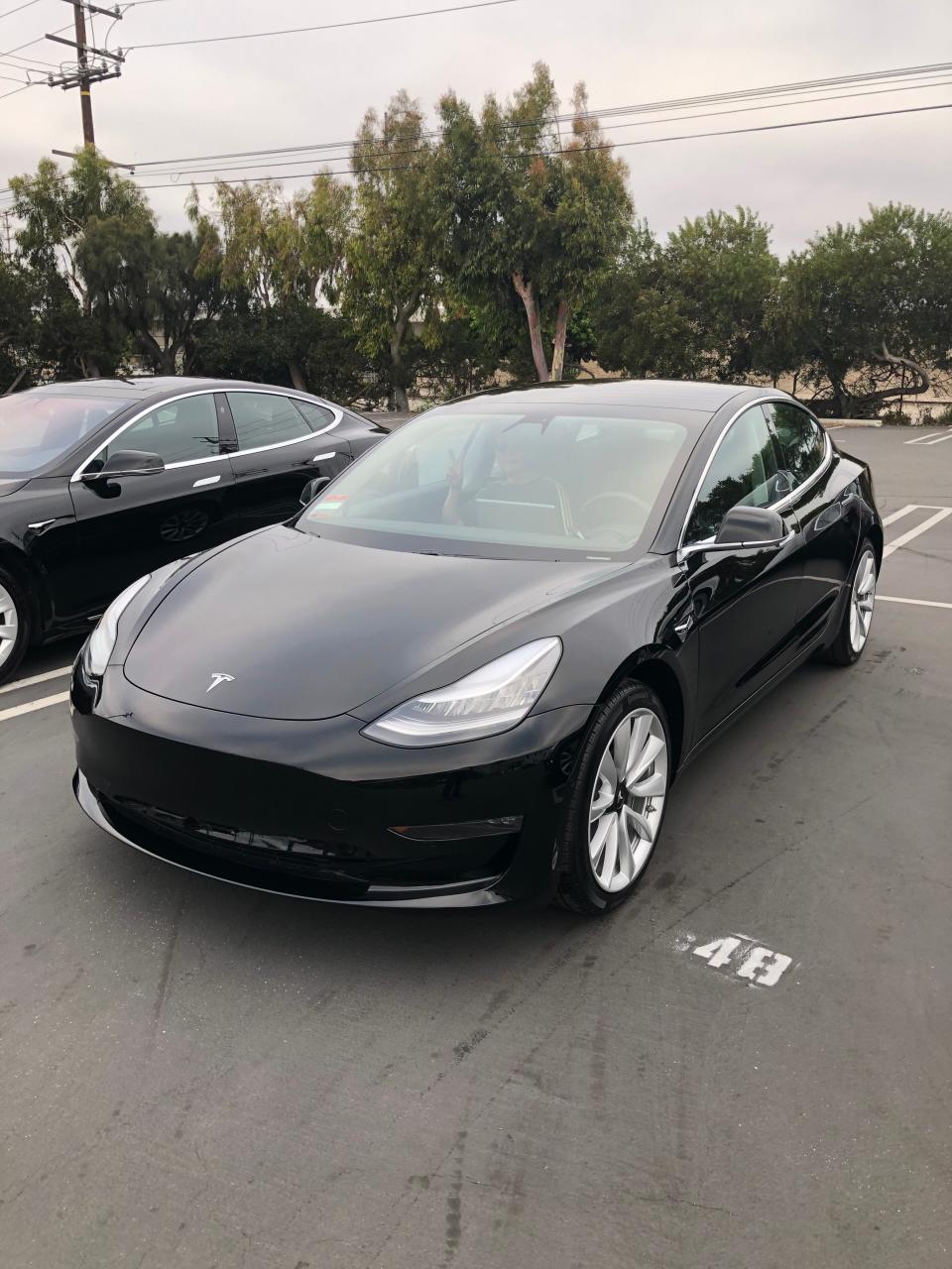 A black Tesla parked in a lot.