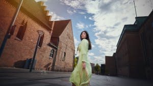 Model outdoors in city / street. Woman in green dress walking