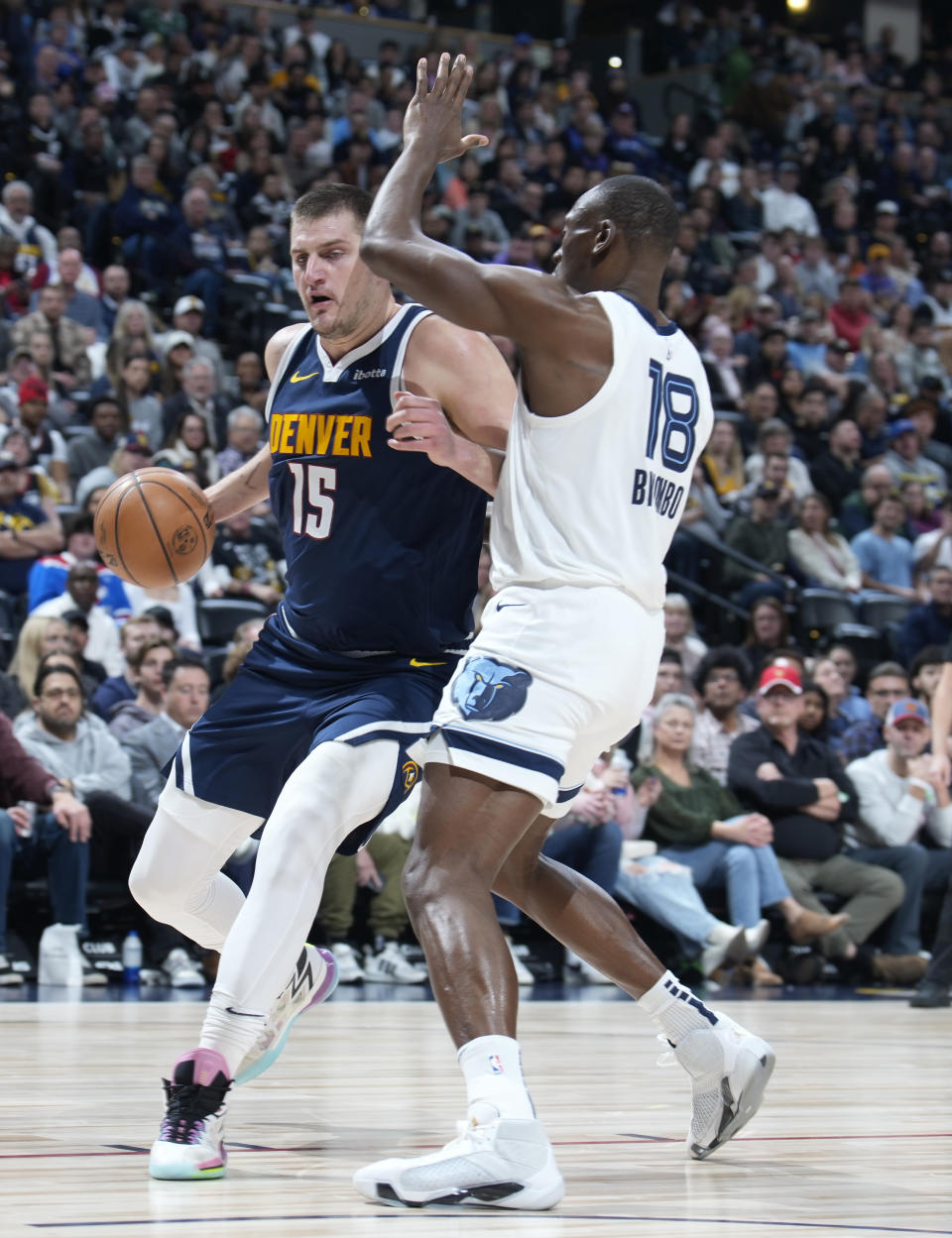 Denver Nuggets center Nikola Jokic, left, drives to the basket as Memphis Grizzlies center Bismack Biyombo, right, defends in the first half of an NBA basketball game Thursday, Dec. 28, 2023, in Denver. (AP Photo/David Zalubowski)