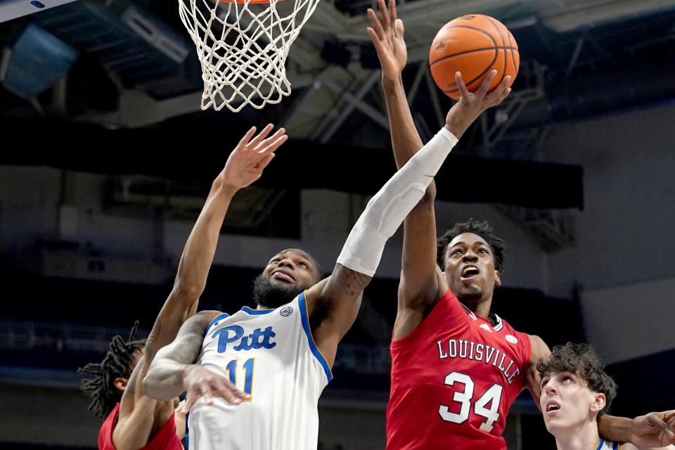 Pittsburgh guard Jamarius Burton (11) lays the ball up in front of Louisville forward Emmanuel Okorafor (34) in a game at Pitt.