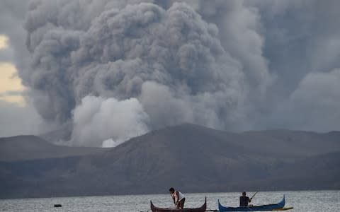 Residents living along Taal lake catch fish in the shadow of the volcano - Credit: Ted Aljibe/AFP