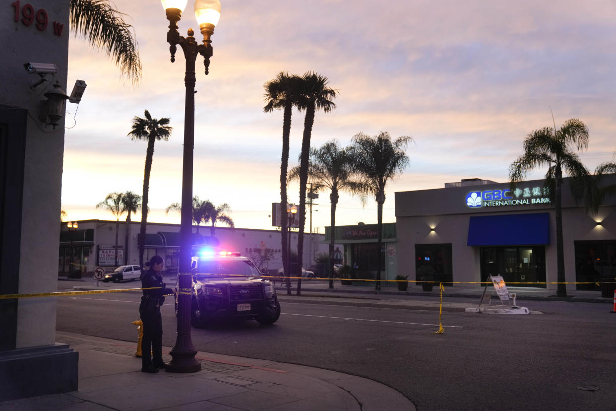 A police officer ties tape around a light pole in Monterey Park, Calif., Sunday, Jan. 22, 2023. A mass shooting took place at a dance club following a Lunar New Year celebration, setting off a manhunt for the suspect. (AP Photo/Jae C. Hong)