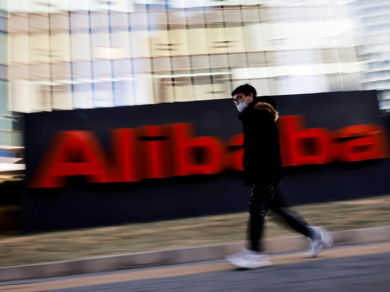 man walks past alibaba logo at headquarters