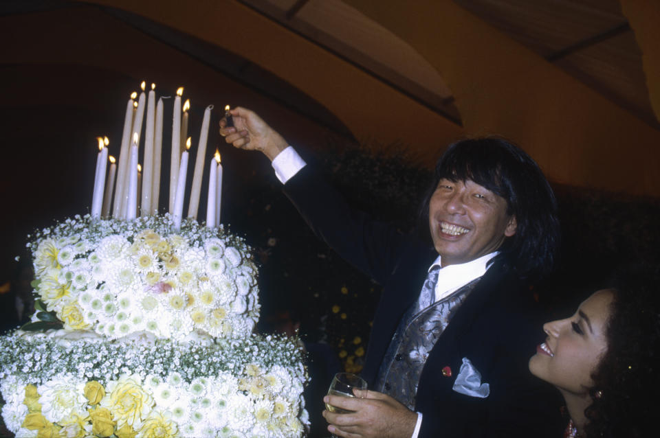 Japanese designer Kenzo Takada lights the candles on a large flower-covered cake. He is showing his women's 1991 spring-summer ready-to-wear line in Paris. (Photo by Pierre Vauthey/Sygma/Sygma via Getty Images)