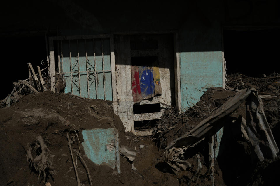 A Venezuelan flag hangs at a home full of mud where the search for bodies continues after flooding Las Tejerias, Venezuela, Monday, Oct. 10, 2022. A fatal landslide fueled by flooding and days of torrential rain swept through this town in central Venezuela. (AP Photo/Matias Delacroix)G