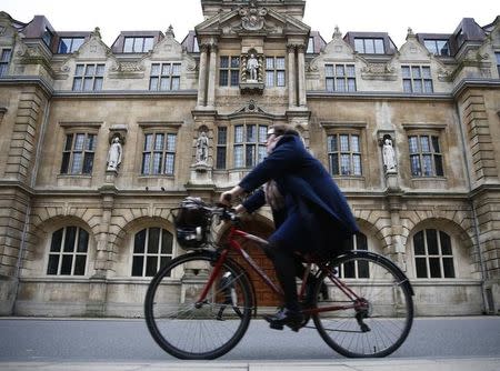 A woman rides a bike next to the Oriel College building with the statue of Cecil Rhodes on its facade in Oxford, southern England, December 30, 2015. REUTERS/Eddie Keogh/Files