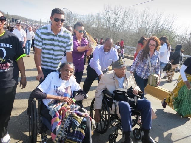 This image provided by Elliott Smith shows Elliott Smith, second from left, pushing his great-aunt, the late civil right activist Amelia Boynton, in a wheelchair across the Edmund Pettus Bridge in Selma, Ala., during a 2015 commemoration of the Selma to Montgomery voting rights marches. Now, at 27, Smith himself is in Selma leading a multiracial delegation of millennial and Gen Z activists, carrying on the legacy of the movement’s original foot soldiers. (Elliott Smith via AP)