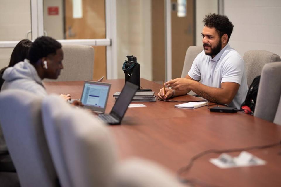 Isiah Caldwell, who teaches English at Crooked Oak Middle School, helps high school seniors fill out their application to attend the University of Oklahoma.