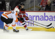 New Jersey Devils defenseman Ryan Graves (33) passes the puck as Philadelphia Flyers defenseman Rasmus Ristolainen (70) defends during the second period of an NHL hockey game Sunday, Nov. 28, 2021, in Newark, N.J. (AP Photo/Bill Kostroun)