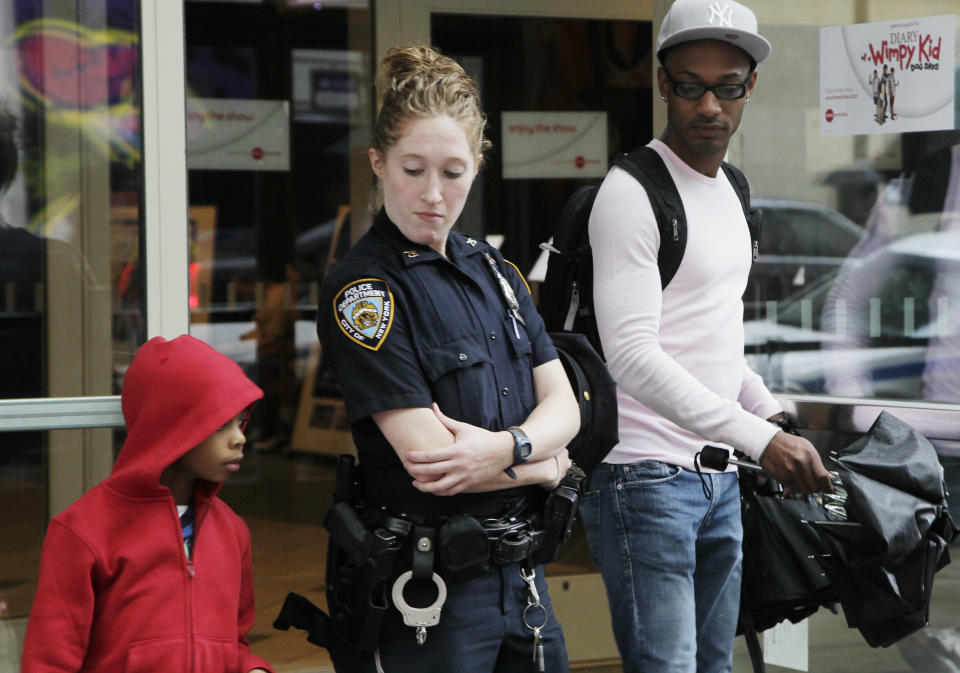 A New York City police officer watches as movie patrons arrive for a screening of "The Dark Knight Rises," Friday, July 20, 2012 in New York. A gunman in a gas mask barged into a crowded Denver-area theater during a midnight premiere of the Batman movie on Friday, hurled a gas canister and then opened fire, killing 12 people and injuring at least 50 others in one of the deadliest mass shootings in recent U.S. history. NYPD commissioner Ray Kelly said the department was providing the extra security at theaters "as a precaution against copycats and to raise the comfort levels among movie patrons." (AP Photo/Mark Lennihan)