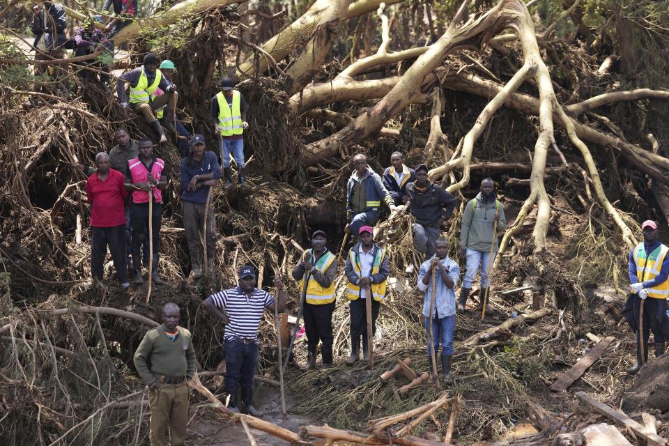 People gather on a bridge where a woman's body was retrieved after floodwater washed away houses, in Kamuchiri Village Mai Mahiu, Nakuru County, Kenya, Tuesday, April 30, 2024. Kenya, along with other parts of East Africa, has been overwhelmed by flooding that killed 66 people on Monday alone and in recent days has blocked a national highway, swamped the main airport and swept a bus off a bridge. More than 150,000 people are displaced and living in dozens of camps. (AP Photo/Brian Inganga)