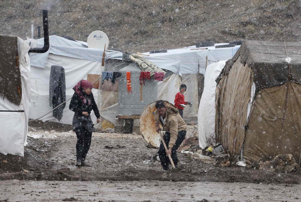 A Syrian refugee works outside his tent during a winter storm in Zahle town, in the Bekaa Valley December 11, 2013. The worst of winter is yet to come for 2.2 million refugees living outside Syria and millions more displaced inside the country. A storm named Alexa is sweeping across Syria and Lebanon, bringing with it high winds and freezing temperatures - and marking the beginning of the third winter since the Syrian conflict began in March 2011. In the tented settlement a few kilometres from the border in Lebanon's Bekaa Valley, more than 1,000 people live in rudimentary shelters. REUTERS/Mohamed Azakir (LEBANON - Tags: POLITICS CIVIL UNREST CONFLICT SOCIETY IMMIGRATION ENVIRONMENT ENERGY TPX IMAGES OF THE DAY)