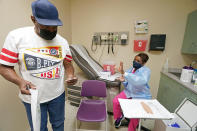 Wilbert Marshall, 71, looks at his shot card after receiving the COVID-19 vaccine from Melissa Banks, right, a nurse at the Aaron E. Henry Community Health Service Center in Clarksdale, Miss., Wednesday, April 7, 2021. Marshall was among a group of seniors from the Rev. S.L.A. Jones Activity Center for the Elderly who received their vaccinations. More Black Americans say they are open to taking the coronavirus vaccine amid campaigns to overcome a shared historical distrust of science and government. (AP Photo/Rogelio V. Solis)