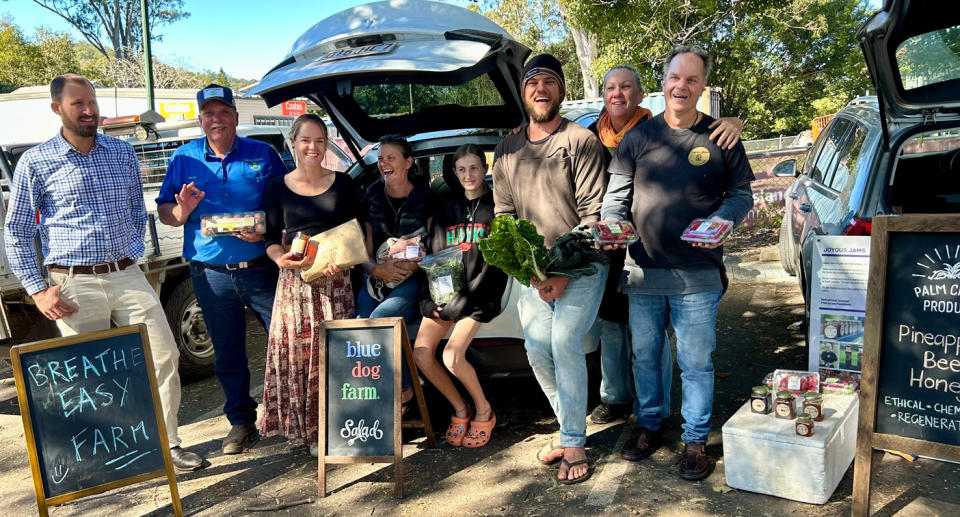 Producers lined up next to open car boots holding their products.