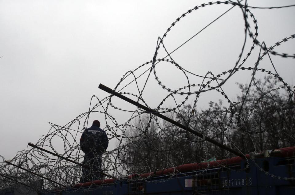 A Hungarian police officer stands guard at Serbia's border with Hungary near a makeshift camp for migrants in Horgos, Serbia, Wednesday, Feb. 8, 2017. European Commission Vice-President Frans Timmermans said Wednesday that it is "highly urgent" for countries to live up to their pledges, with the legally binding scheme set to expire in September. (AP Photo/Darko Vojinovic)