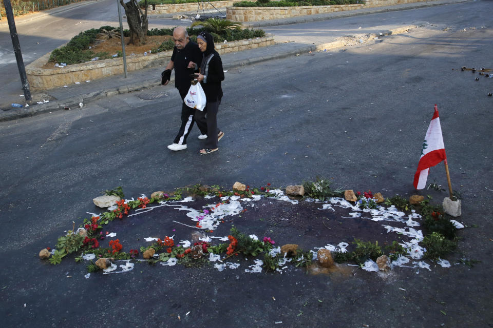 Lebanese people pass by the scene where a local official for a Lebanese political party was shot dead, in Khaldeh, south of Beirut, Lebanon, Wednesday, Nov. 13, 2019. Protesters had poured into the streets across Lebanon after President Michel Aoun said the formation of a new government might be delayed. (AP Photo/Hussein Malla)