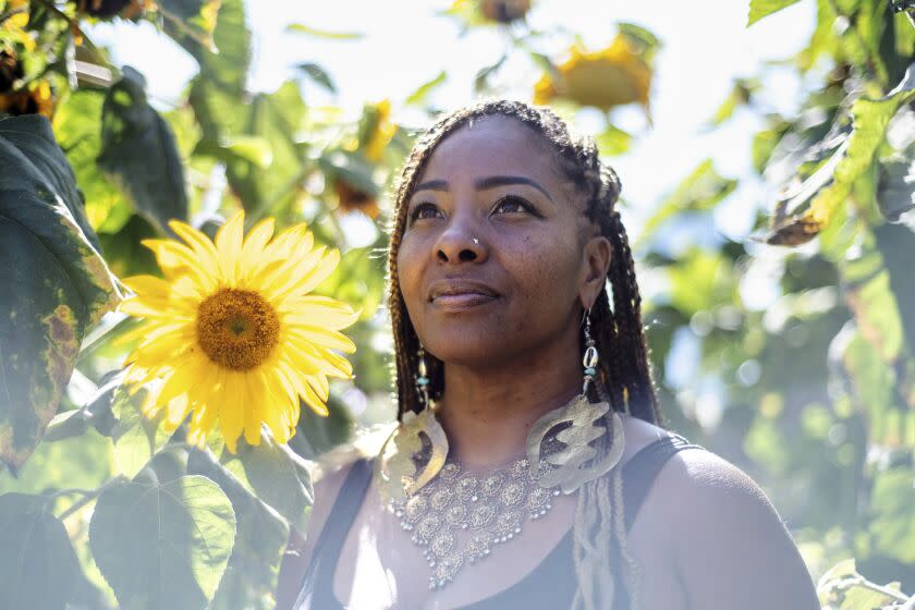 A woman stands amid sunflowers.