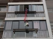 Resident pulls back a rope tying groceries delivered by community workers as the residential compound is under sealed management, following an outbreak of the novel coronavirus, in Yichang, Hubei