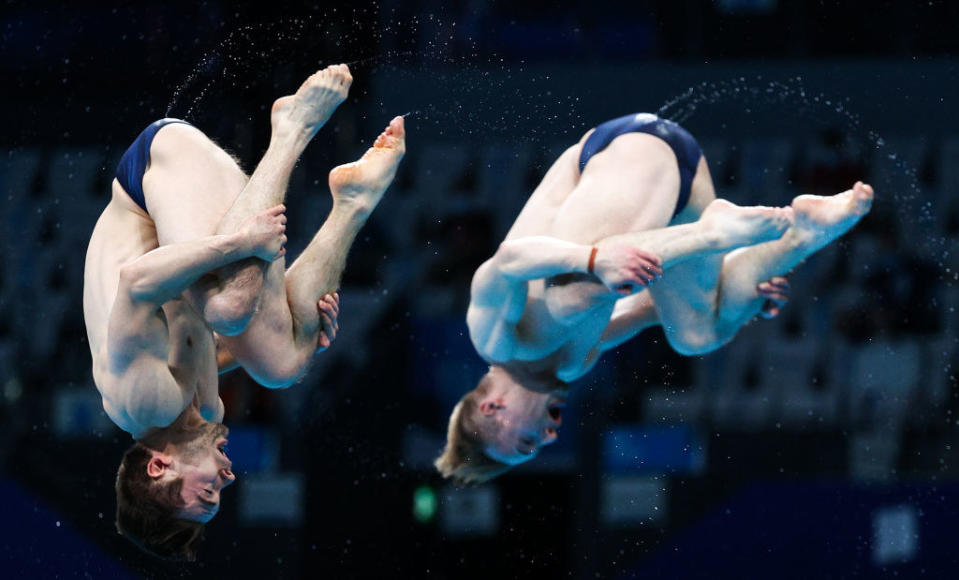 Water flying off the speedos of divers as they head towards the water